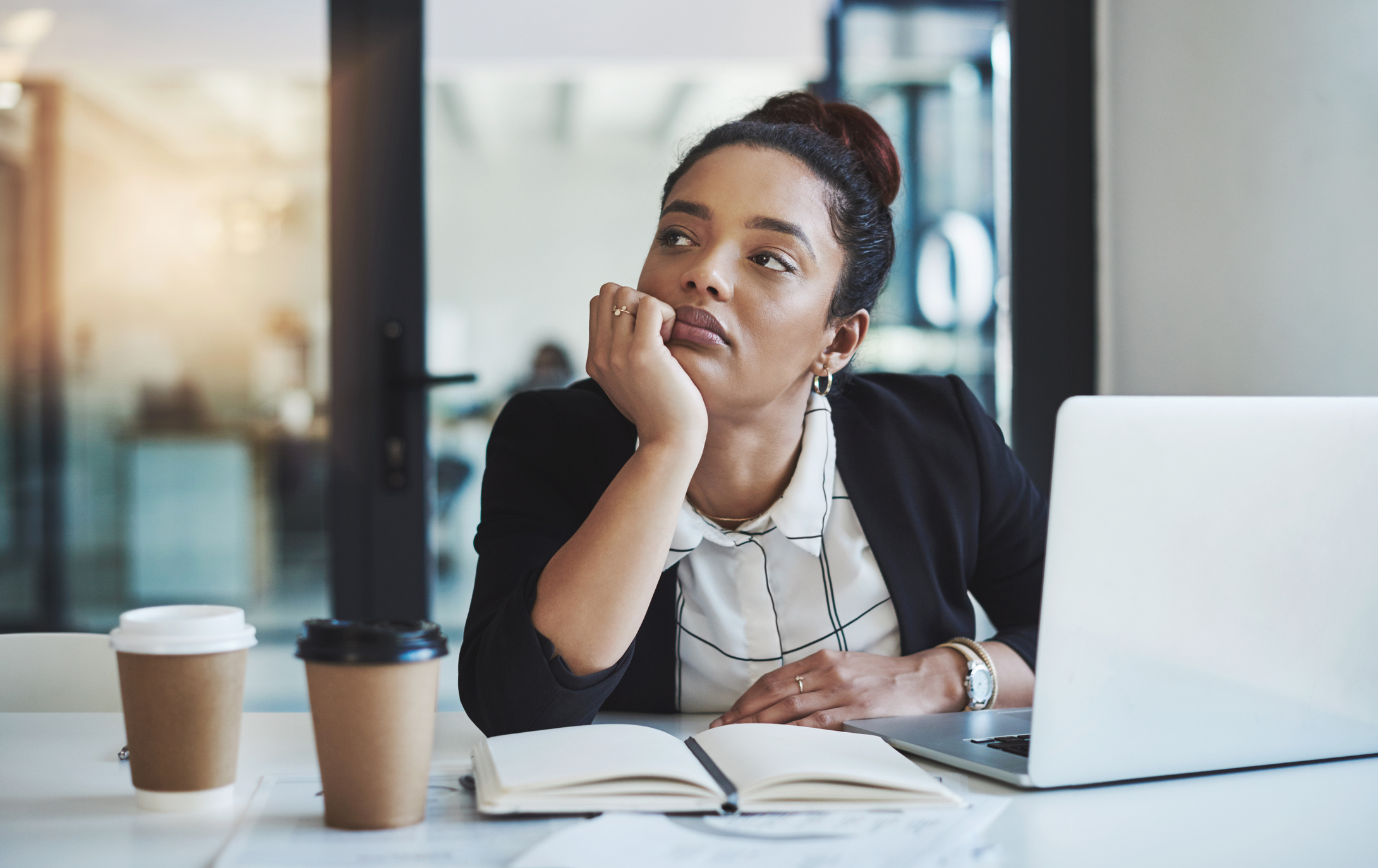 Shot of a young businesswoman looking bored while working at her desk in a modern office