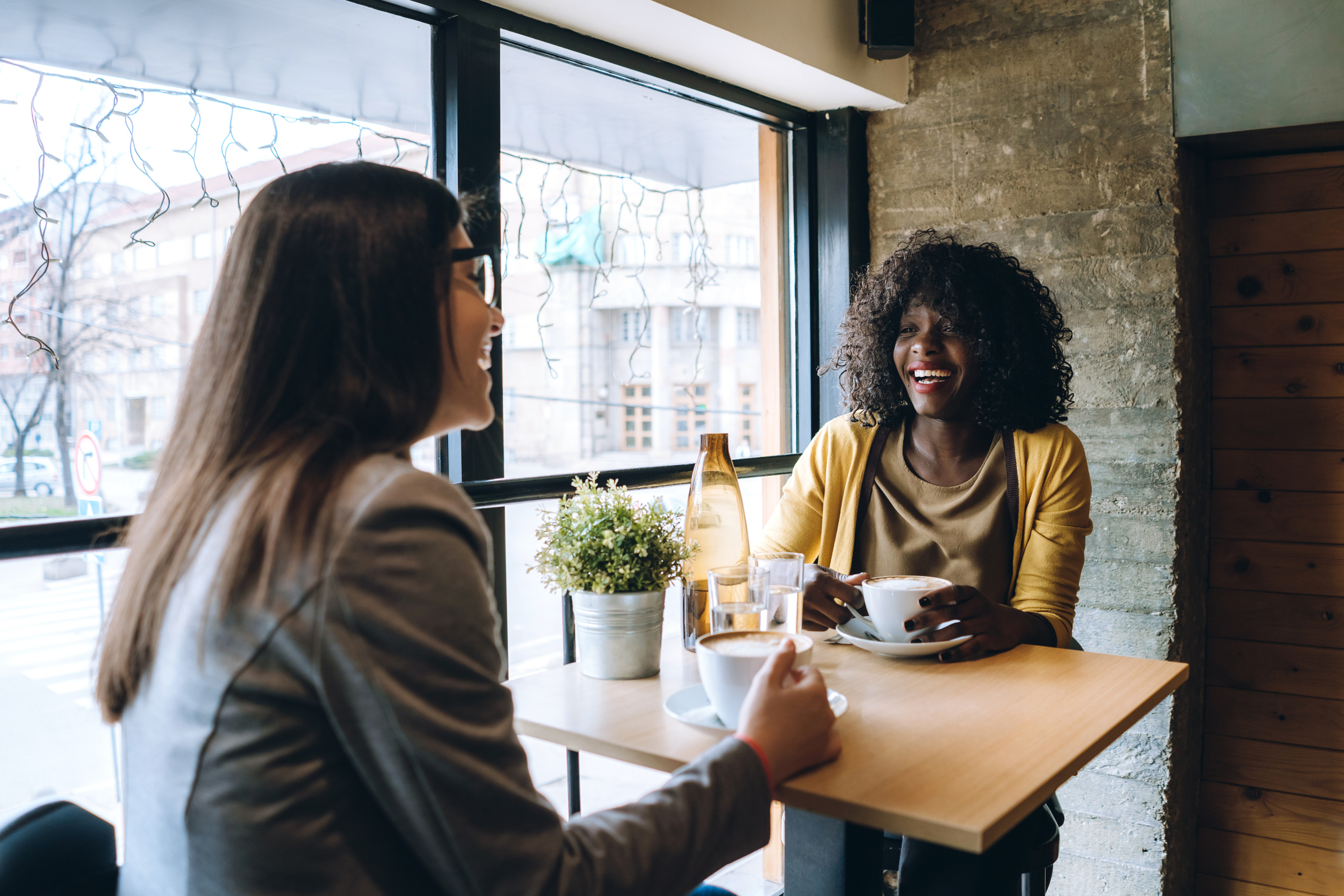Multiethnic female friends are chatting and drinking coffee in downtown café